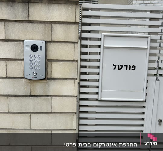 אינטרקום עם מצלמה ומקשים על קיר לבנים